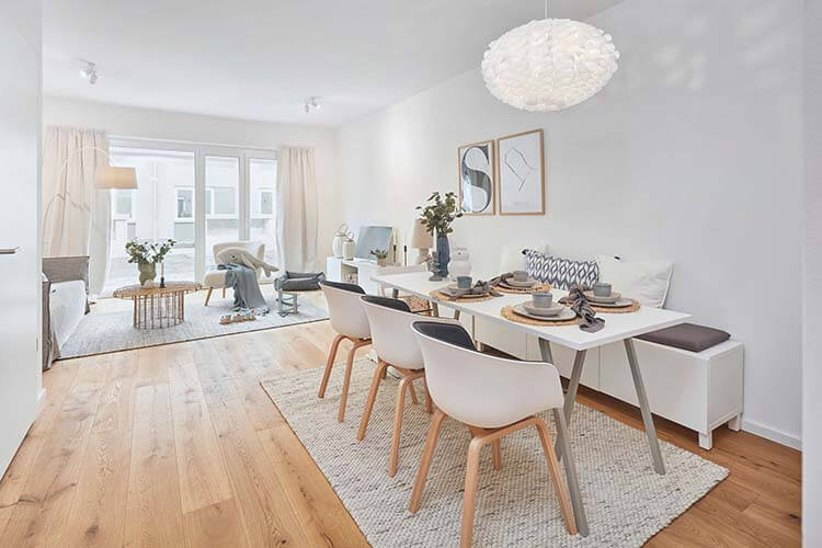 Wohnzimmer im Muster-Stadhaus des Neubauprojektes Constanze mit Esstisch im Vordergrund und Sofalandschaft im Hintergrund